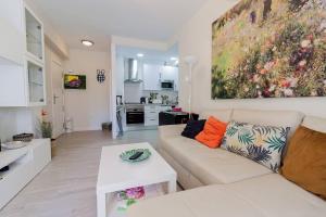 uma sala de estar com um sofá branco e uma pintura na parede em Victoria - Apartamento Playa em Cádiz