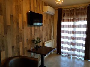 ein Wohnzimmer mit einem Tisch und einem TV an der Wand in der Unterkunft pensiunea grecu in Lugoj
