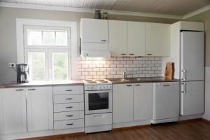 a white kitchen with white cabinets and a window at Hakoniemi in Oravisalo