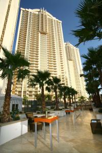 a row of tables and palm trees in front of tall buildings at Luxury Suites International at The Signature in Las Vegas