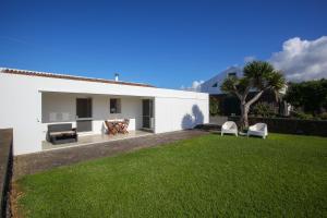 a white house with a green lawn in the yard at Casa do Pico Arde in Ribeira Grande