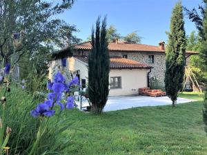 a house with a yard with purple flowers at Podere Badia Valdrago Agriturismo Mugello Circuit in Scarperia