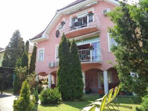 różowy dom z balkonem i drzewami w obiekcie Maria Apartman w Hévízie