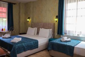 a bedroom with two beds with blue curtains and windows at Doruk Hotel in Ayvalık