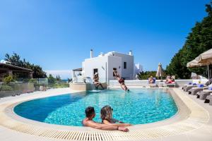 Dos personas sentadas en la piscina de un complejo en Villa Alyko en Aliko Beach