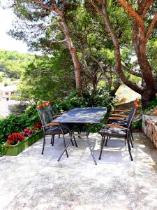 une table et des chaises assises sur une terrasse dans l'établissement Apartment Teuta, à Žirje