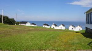a row of houses on a hill next to the ocean at Hôtel Motel du Rocher in Rivière-la-Madeleine