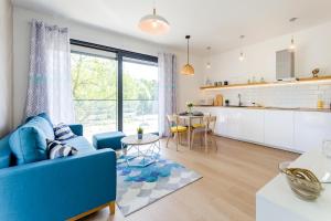 a living room with a blue couch and a kitchen at Helskie Tarasy in Hel