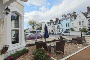 a patio with chairs and an umbrella on a city street at Clifton Villa Guest House in Llandudno