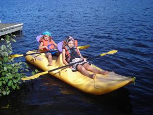 two girls are sitting in a yellow kayak on the water at Le Chalet Bois Rond Relax in Saint-Tite-des-Caps
