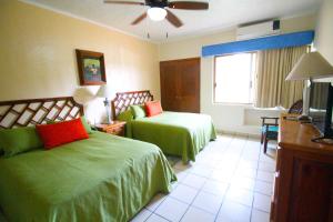 a hotel room with two beds and a flat screen tv at Villas del Sol en Los Tules in Puerto Vallarta