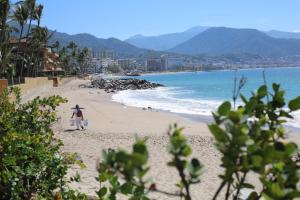 een persoon die op een strand in de buurt van de oceaan loopt bij Villas del Sol en Los Tules in Puerto Vallarta