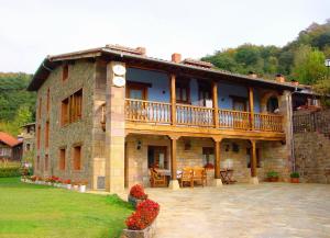 a large stone house with a balcony on top of it at Apart con piscina Lebanes Picos de Europa in Torices