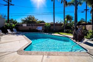 - une piscine dans une cour avec des palmiers dans l'établissement Regency Inn & Suites Downey, à Downey