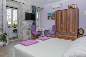 um quarto com uma cama com cadeiras roxas e uma secretária em Devivi Apartments em Split