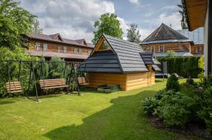 a wooden cabin with a black roof in a yard at Dom Wypoczynkowy Julia in Białka Tatrzańska
