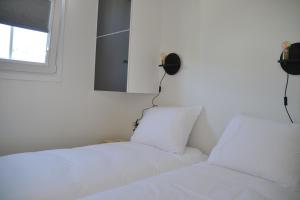 a bedroom with two white beds and a window at Minicamping Shalom in Domburg