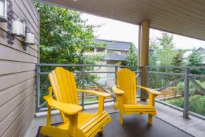 dwa żółte krzesła siedzące na ganku domu w obiekcie 09 Valhalla w mieście Whistler