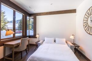 1 dormitorio con cama, escritorio y reloj en 3354 Peak Drive, en Whistler