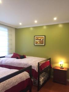 1 Schlafzimmer mit 2 Betten und einer grünen Wand in der Unterkunft Fontana: Location + Pool in Quito