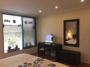 a bedroom with a desk with a computer and a window at Fontana: Location + Pool in Quito