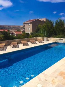 a swimming pool with chairs and a building in the background at Villa Antea - modern house with pool in Pag