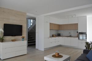 a kitchen with white cabinets and a flat screen tv at Villa Antea - modern house with pool in Pag