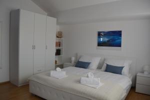 a white bedroom with a large white bed with two pillows at Villa Antea - modern house with pool in Pag +34 photos