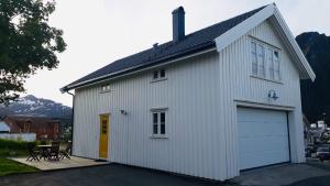 a large white building with a garage at Svinøya, hyggelig leilighet in Svolvær +14 photos