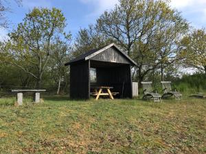 a shed with a picnic table and chairs in a field at BB-Vadehavet Ferielejlighed til 6 personer ved Nationalpark Vadehavet in Ribe