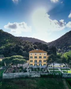 a large yellow building with a mountain in the background at Hotel Villa Casanova in Lucca