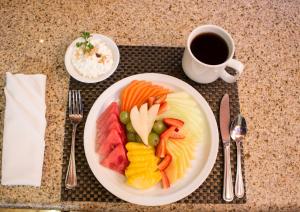a plate of fruit and vegetables on a table with a cup of coffee at Hotel Ticuán in Tijuana