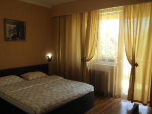 a bedroom with a bed and a window with curtains at Pensiunea Sydney in Timişoara