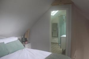a white bedroom with a bed and a bathroom at Belle Vue Terrasse in Giverny