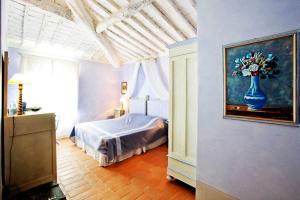 1 dormitorio con 1 cama y una pintura de un jarrón de flores en Podere La Strega, en Siena