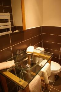 La salle de bains est pourvue d'un lavabo en verre et de toilettes. dans l'établissement Auberge De La Durdent, à Héricourt-en-Caux