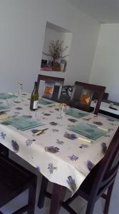uma mesa com uma toalha de mesa branca e uma garrafa de vinho em Gîte O'Cigales em Sablet