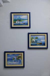 a wall with four framed pictures on it at Mary's room in Samos
