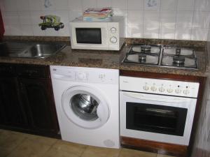 eine Küche mit einer Waschmaschine und einer Mikrowelle in der Unterkunft Moledo Beach - Guest Apartment in Moledo