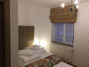 Un dormitorio con una cama y una ventana con una lámpara de araña. en Casa Karola Ház en Băile Tuşnad
