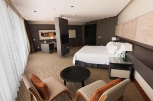 Habitación de hotel con cama, mesa y sillas en Enjoy Antofagasta, en Antofagasta