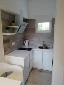 een kleine keuken met witte kasten en een wastafel bij Apartment Kate in Bibinje