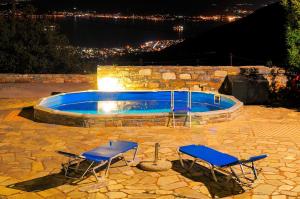 duas cadeiras e uma piscina à noite em Pelion Goddess Villas em Agios Georgios Nilias