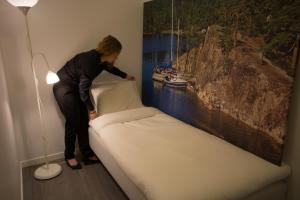 una mujer de pie junto a una cama en una habitación en Jönköping Vandrarhem en Jönköping