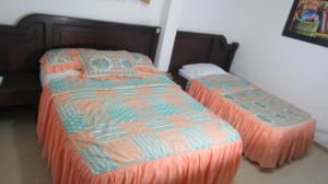 a bedroom with two beds with orange comforters at Hotel Nuevo Tio in Valledupar