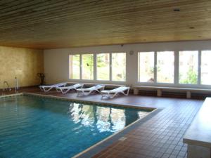 a large swimming pool with white chairs and windows at Ferienwohnung Ritter in Missen-Wilhams