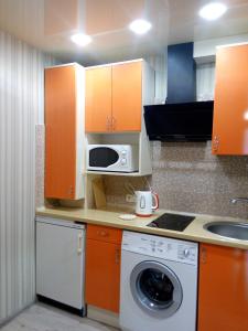 une cuisine avec des armoires orange et un lave-linge dans l'établissement АРТГАЛЕРЕЯ у серці Львова, à Lviv