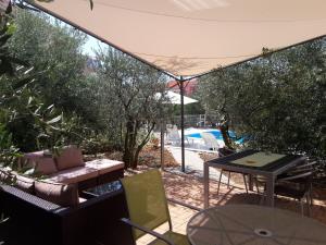 une terrasse avec un parasol, une table et des chaises dans l'établissement Apartments Olive Garden - swimming pool, à Biograd na Moru