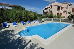 - une piscine avec des chaises longues bleues à côté d'un bâtiment dans l'établissement Apartments Olive Garden - swimming pool, à Biograd na Moru