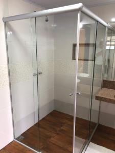 um chuveiro com portas de vidro na casa de banho em João e Maria Restaurante e Chalés em Tiradentes